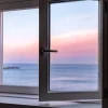 Modern window with a view of a sunset over the ocean