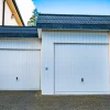 Double garage construction in New Jersey with white doors and paved driveway